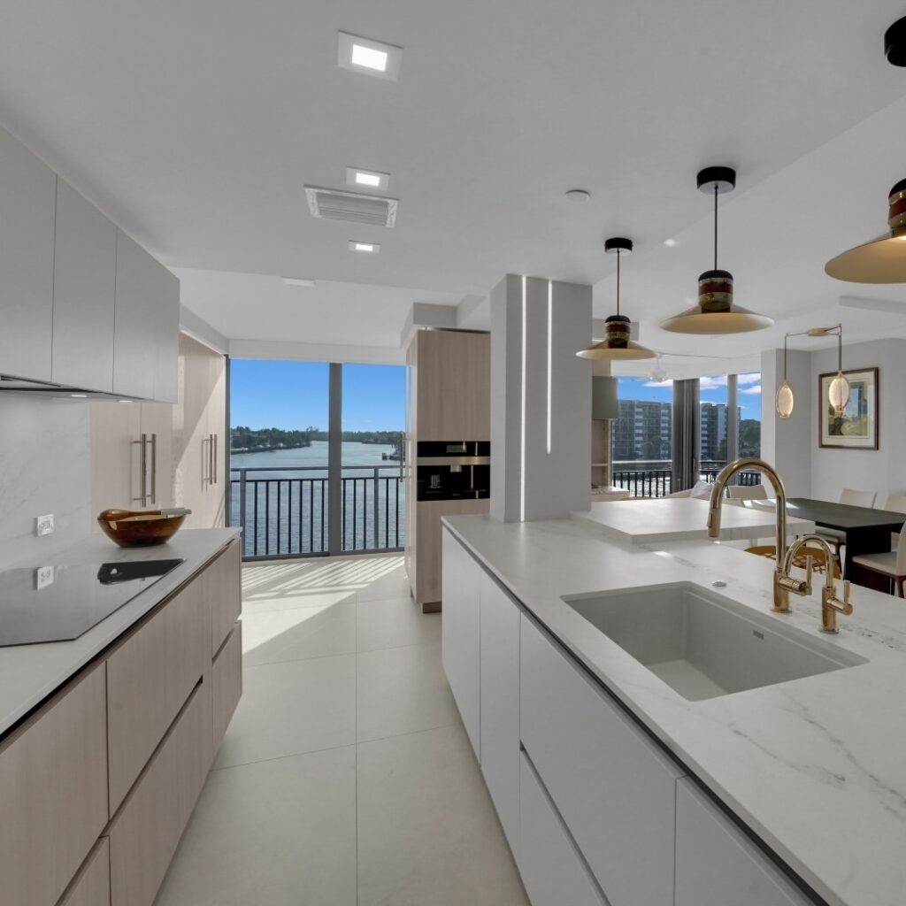 Modern white kitchen overlooking serene waterfront vista.