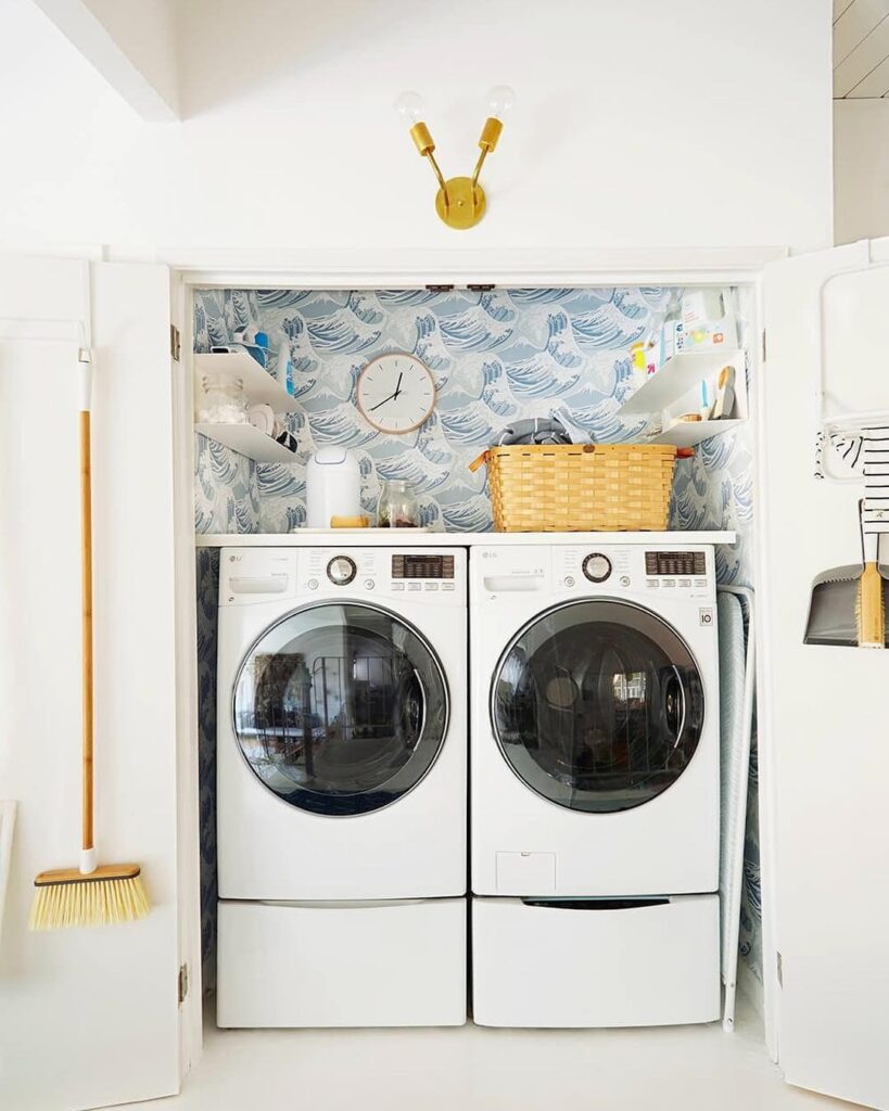 Laundry closet with wave wallpaper and stacked appliances.