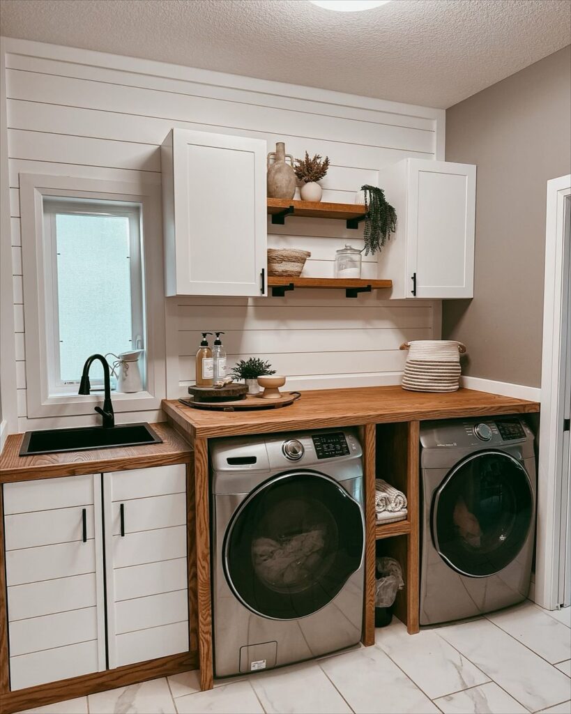 Modern farmhouse laundry room with wooden countertops and silver appliances.