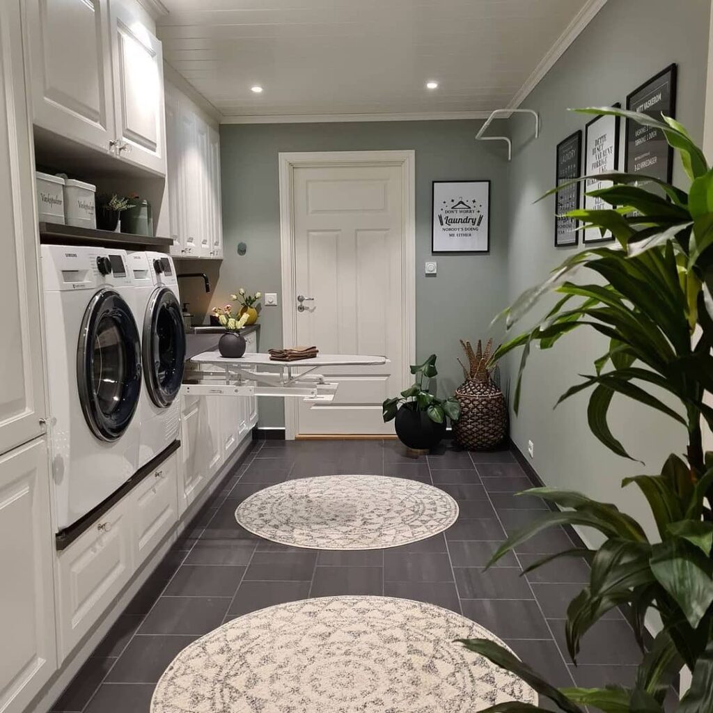 Stylish laundry room with green walls, white appliances, and indoor plants.