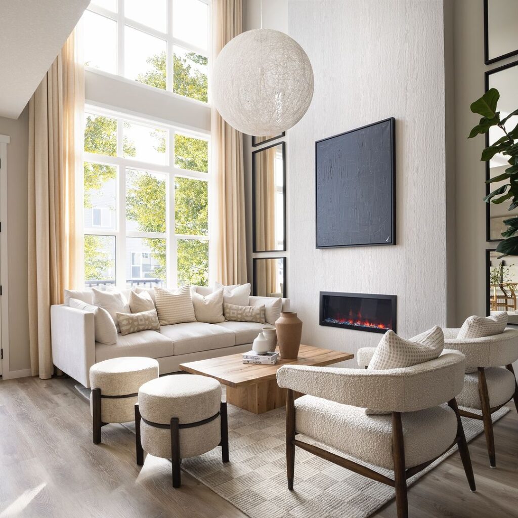 Bright living room with high windows, white furniture, and modern linear fireplace.