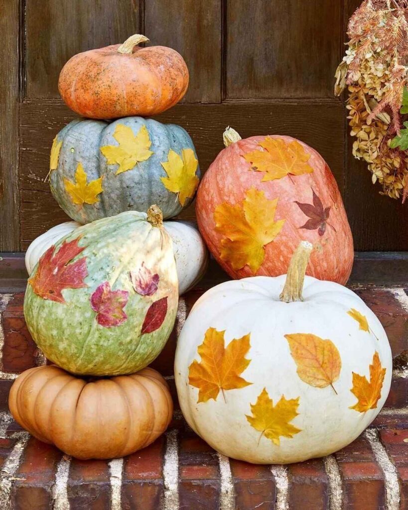 Pumpkins decorated with colorful autumn leaves