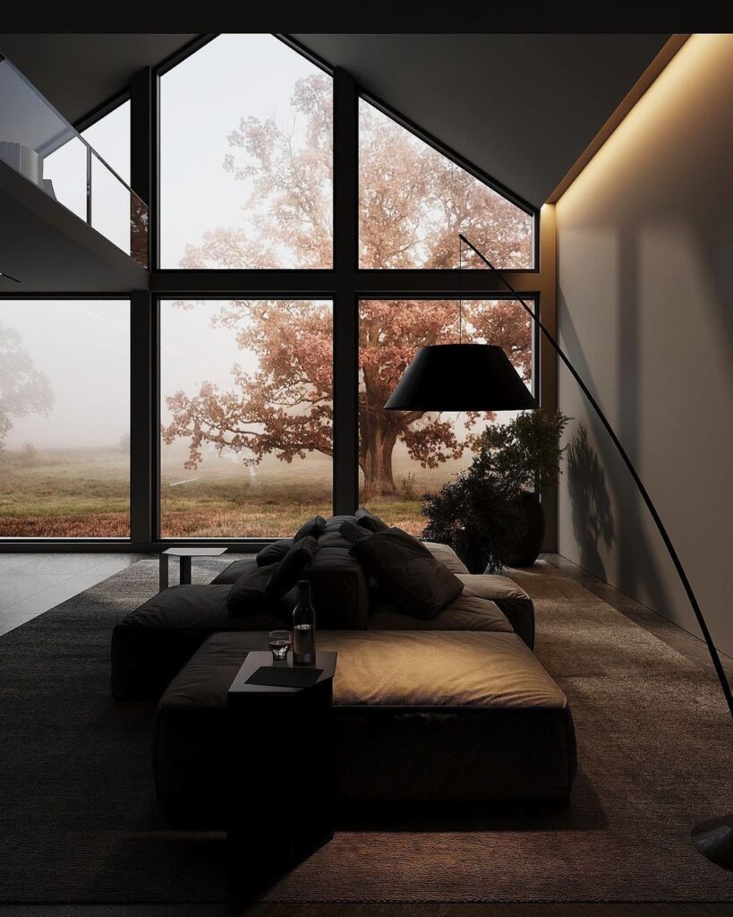 Modern living room with large windows overlooking misty autumn landscape.