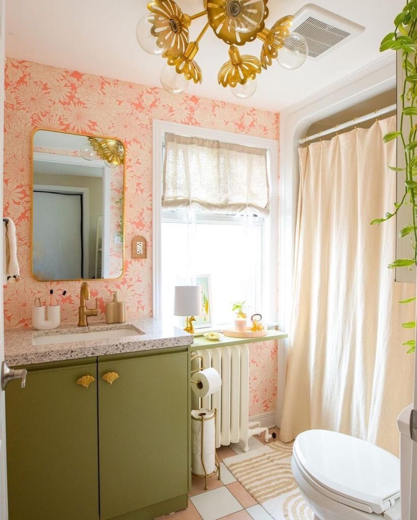 Floral pink bathroom with green vanity and gold accents.