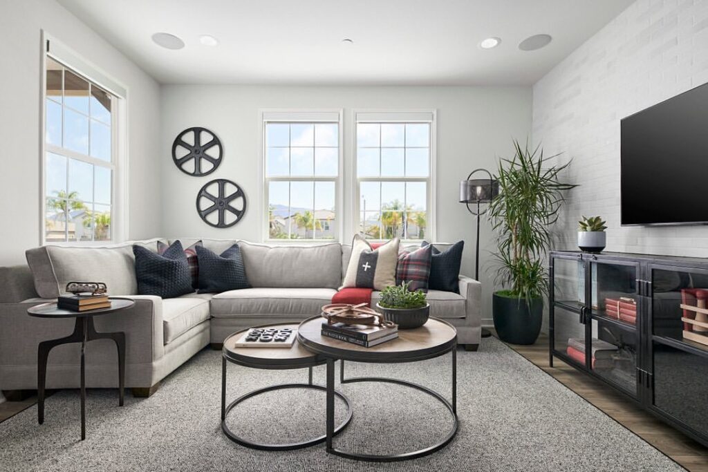 Cozy corner living room with sectional sofa, round coffee tables, and bright windows.