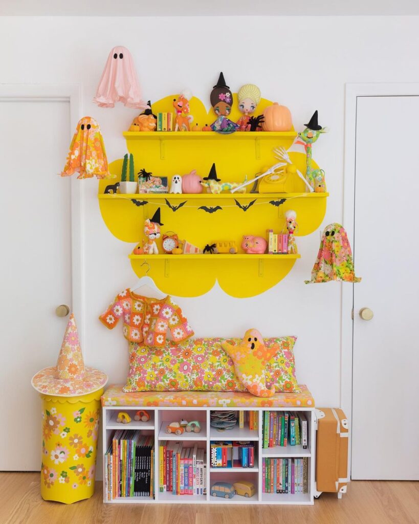 Colorful kids' Halloween corner with yellow shelves and pastel decorations.