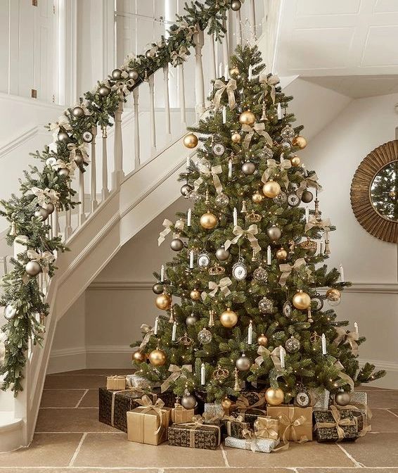 Gold and cream Christmas tree beside white curved staircase with matching garland