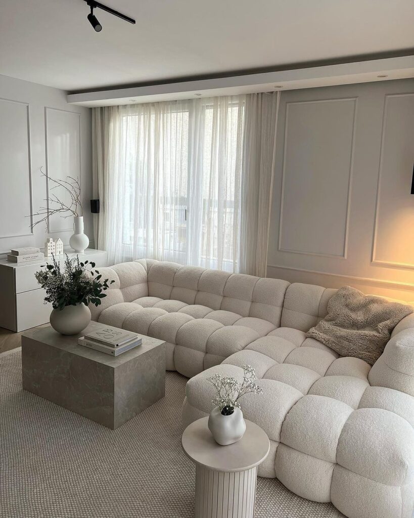 Cozy white living room with large tufted sofa and soft lighting.