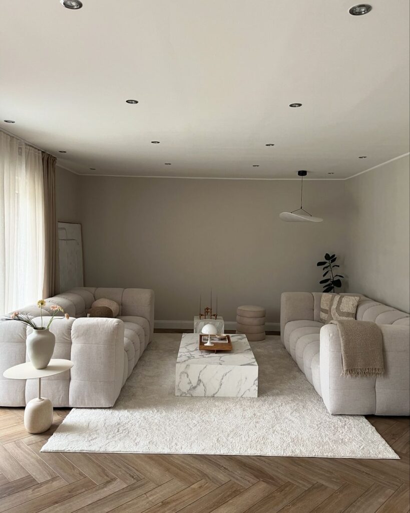 Serene white living room with plush sofas and marble table.