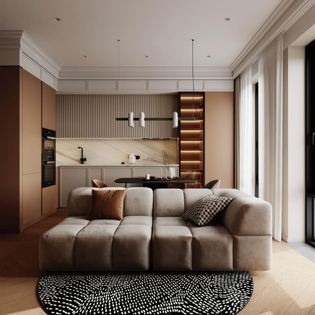 Modern living room with beige sofa, patterned rug, and open kitchen area.
