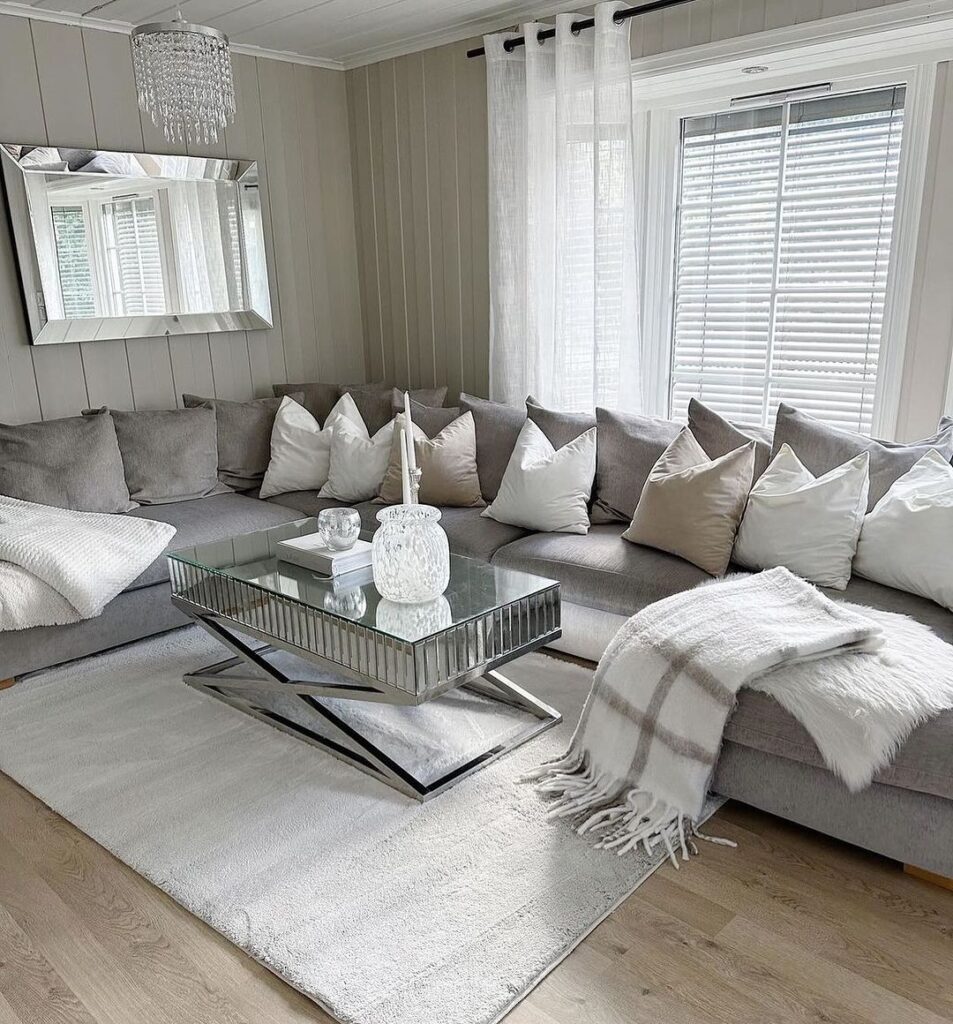 Gray and white living room with plush sectional and crystal chandelier.