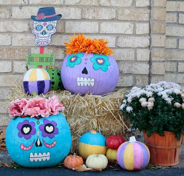 Colorful pumpkins painted as sugar skulls with festive decorations.