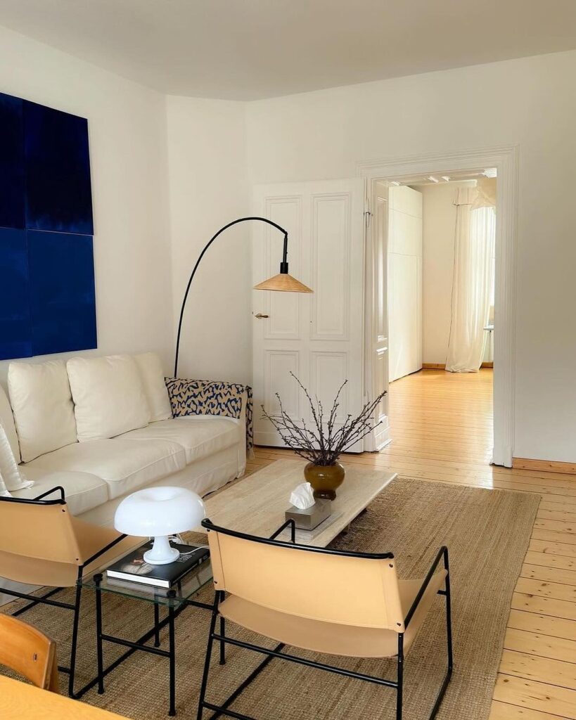 Minimalist living room with navy art and tan chairs.