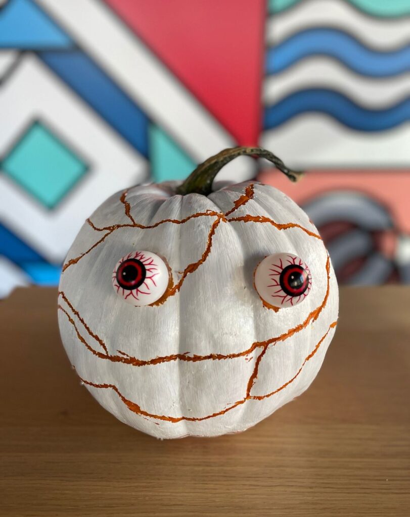 White pumpkin painted as mummy with bulging eyes.