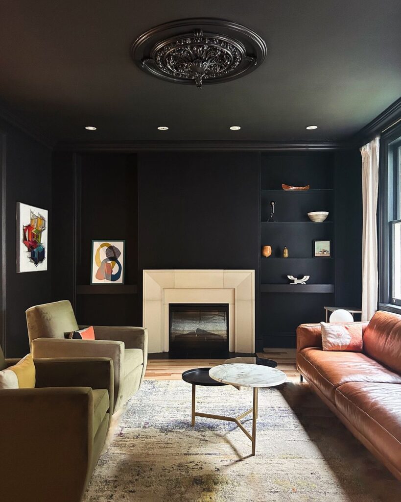 Moody black living room with colorful art and leather sofa.