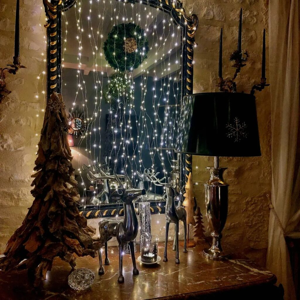 "Mirror Christmas display with fairy lights and metallic deer"