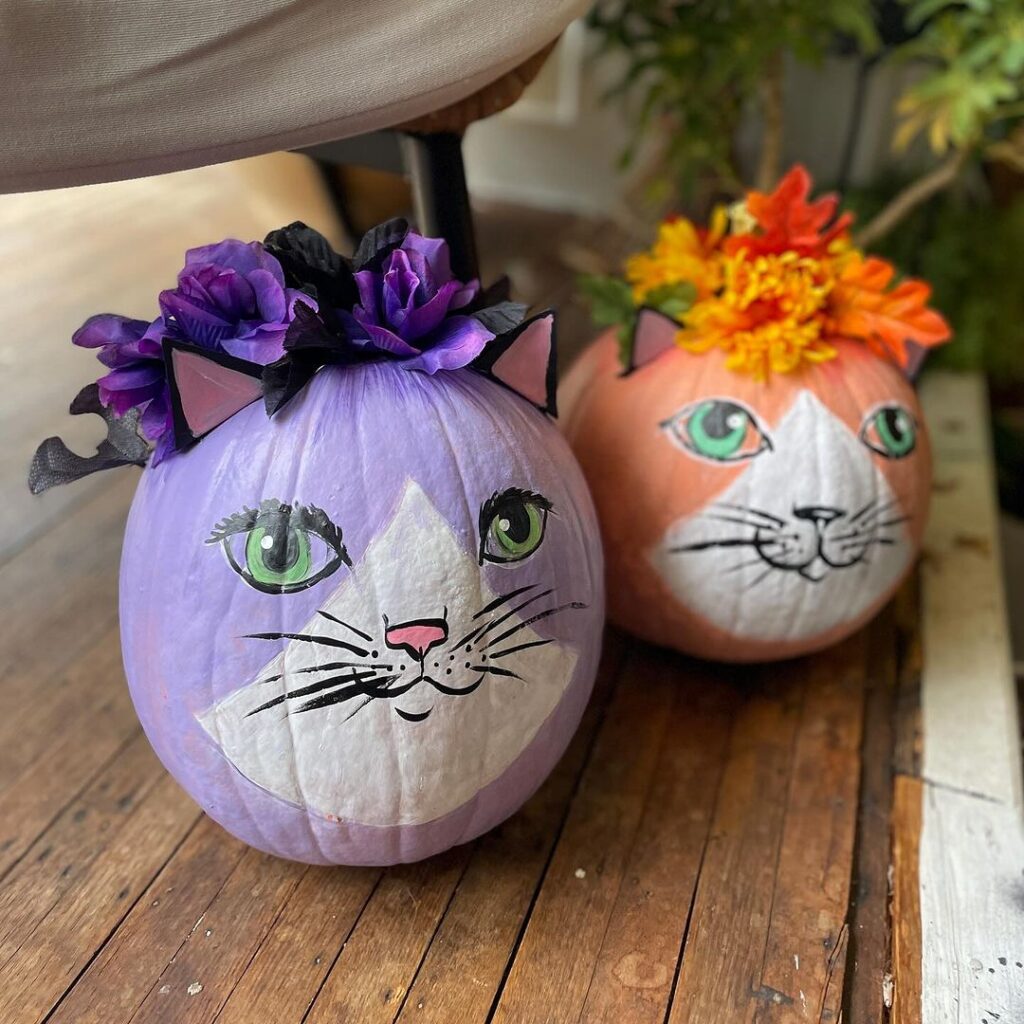 Painted pumpkins as cats with flower crowns.