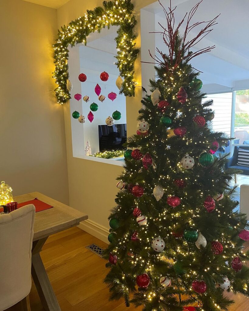 Christmas tree and window decorated with ornaments and lights.