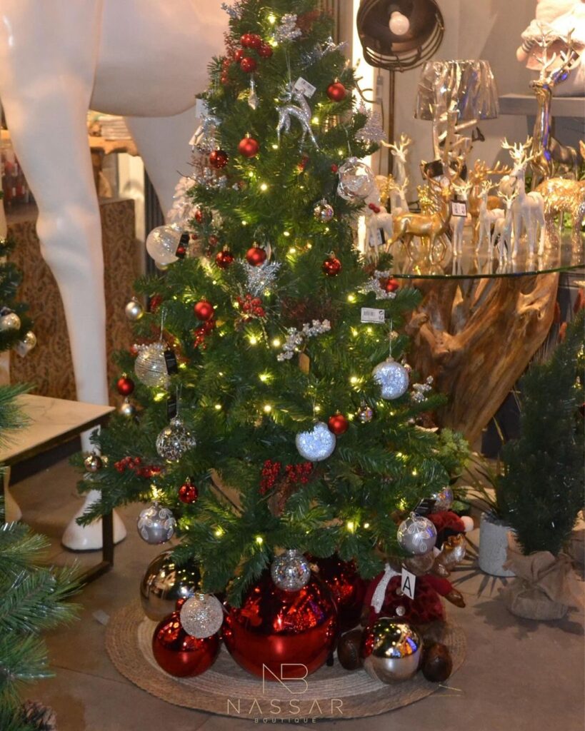 Decorated Christmas tree in store with ornaments and reindeer figurines nearby.