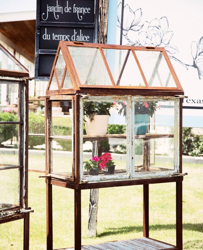 Miniature greenhouse made from old windows on table