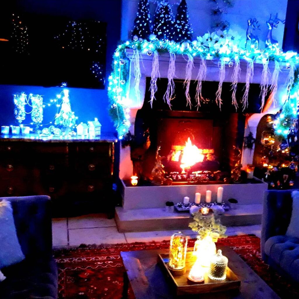 Blue lit Christmas fireplace with icicle decorations and glowing village display