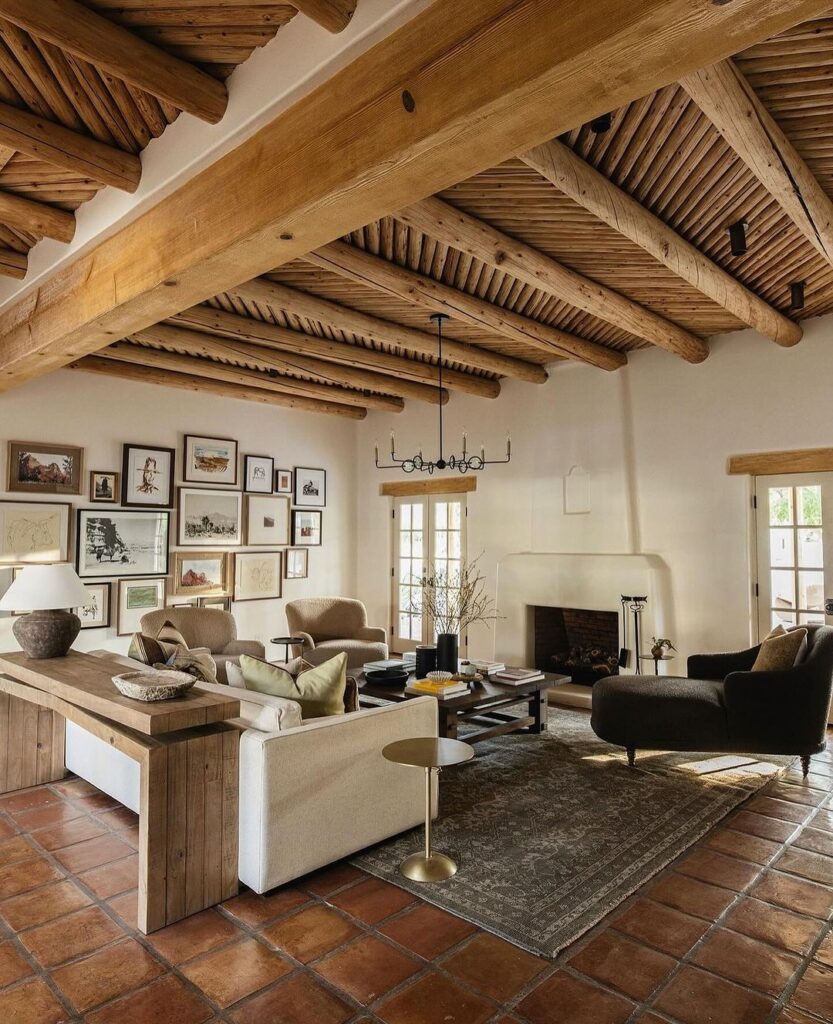 Rustic living room with wooden beam ceiling, gallery wall, and comfortable neutral furniture.