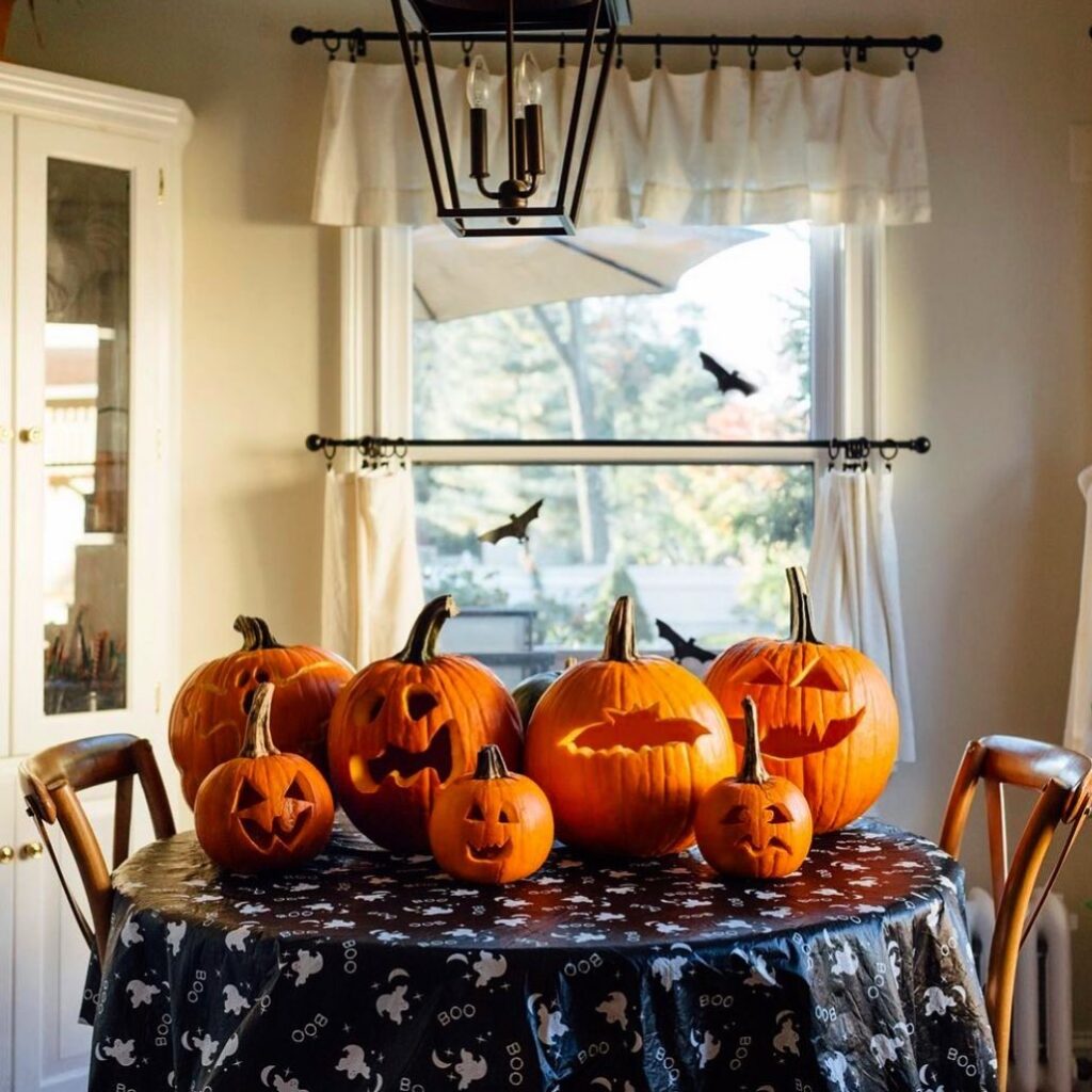 Carved pumpkins on Halloween-themed table by window