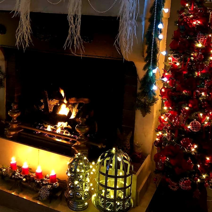 Cozy fireplace with glowing lanterns and red Christmas decor