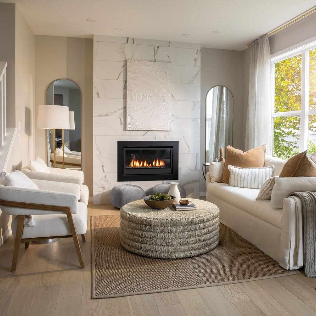 Elegant living room with marble fireplace wall, textured artwork, and neutral furnishings.