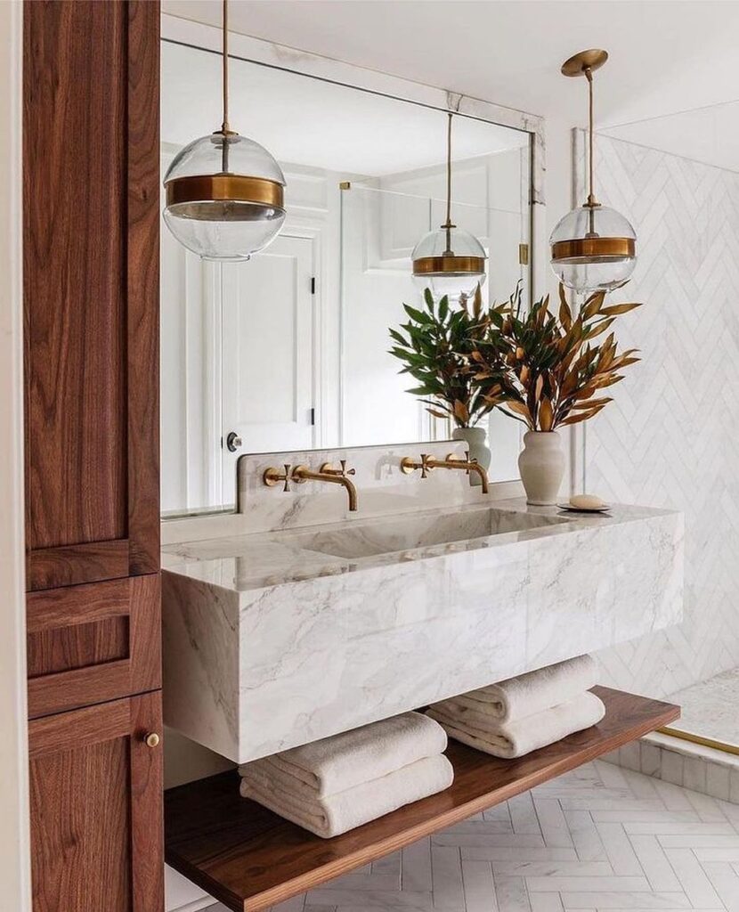 Minimalist bathroom with floating marble sink, globe lights, and wood accents.