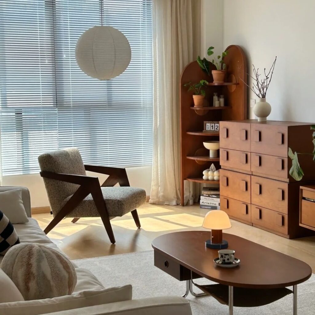 Mid-century modern living room with angular chair, wooden furniture, and abundant natural light.