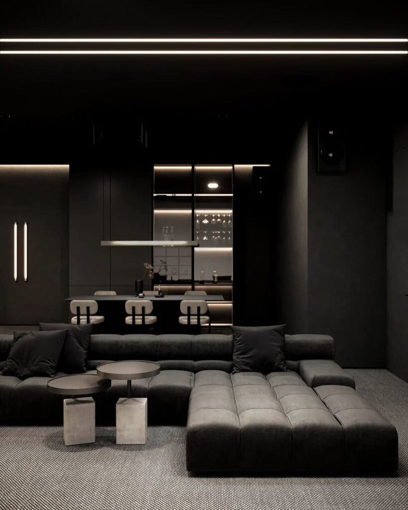 Dark modern living room with large black sectional and sleek kitchen glimpse