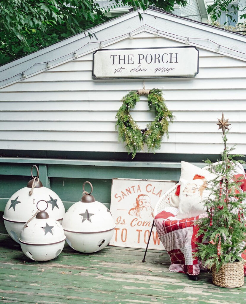 White decorative bells and Santa sign on green porch with wreath