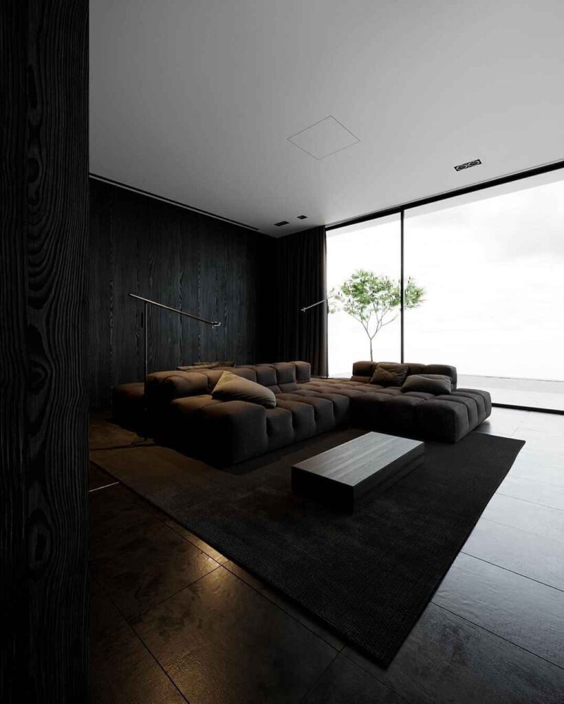 Minimalist black living room with large sofa and window view of tree 