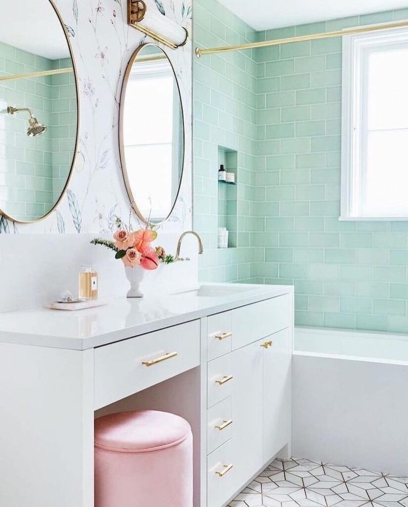 Mint green bathroom with white vanity, gold accents, and pink stool.