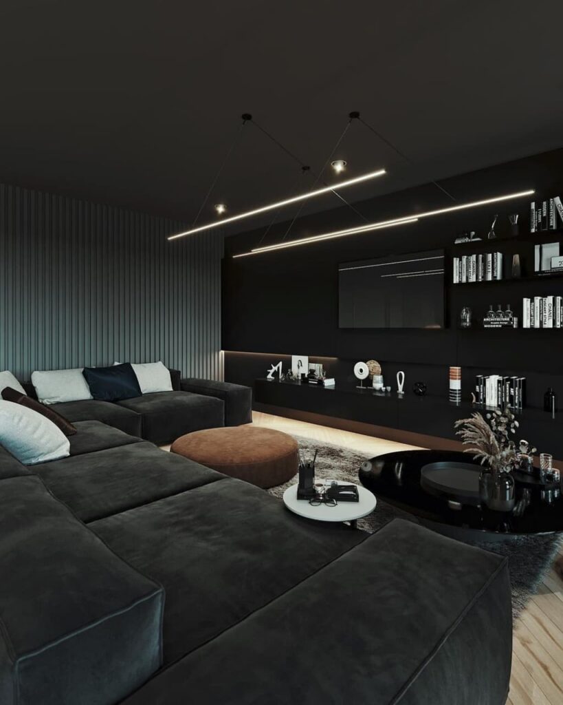 Modern black living room with suspended lighting, sectional sofa, and built-in shelving.