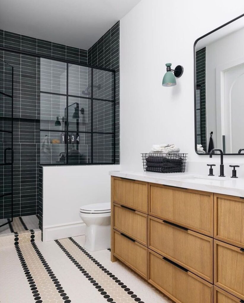 Bathroom with black shower tiles and wooden vanity