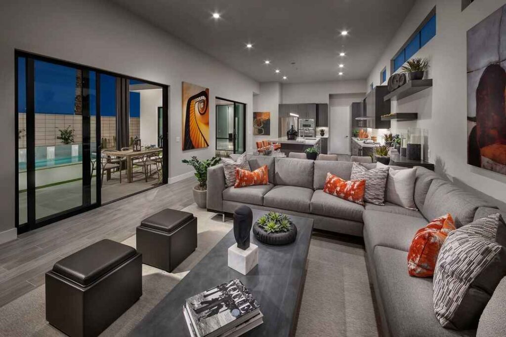 Modern living room with gray sectional and pool view.