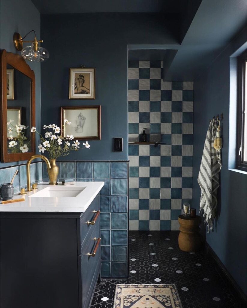 Dark blue bathroom with checkered tiles and brass accents.