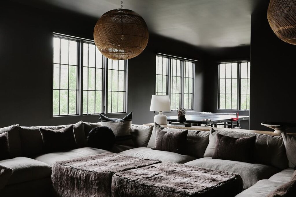 Dark living room with large sectional and woven pendant light.