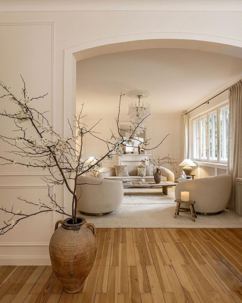 Cozy living room with blooming branches and cream furniture.