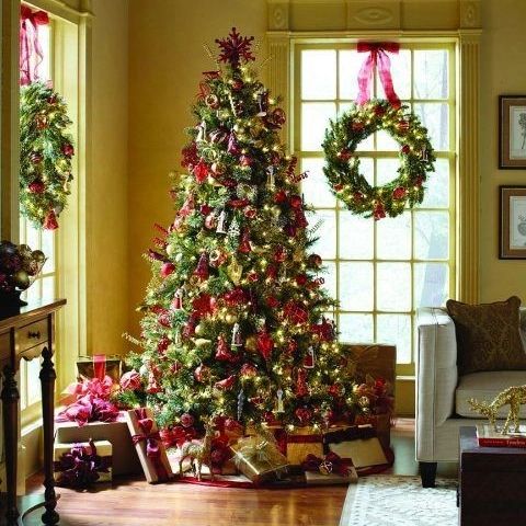 Christmas tree with matching wreaths in sunlit yellow living room corner