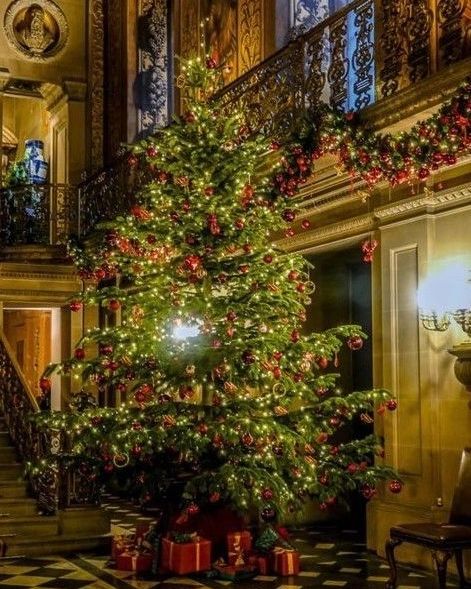 Grand Christmas tree in historic mansion with checkerboard floor and iron railings