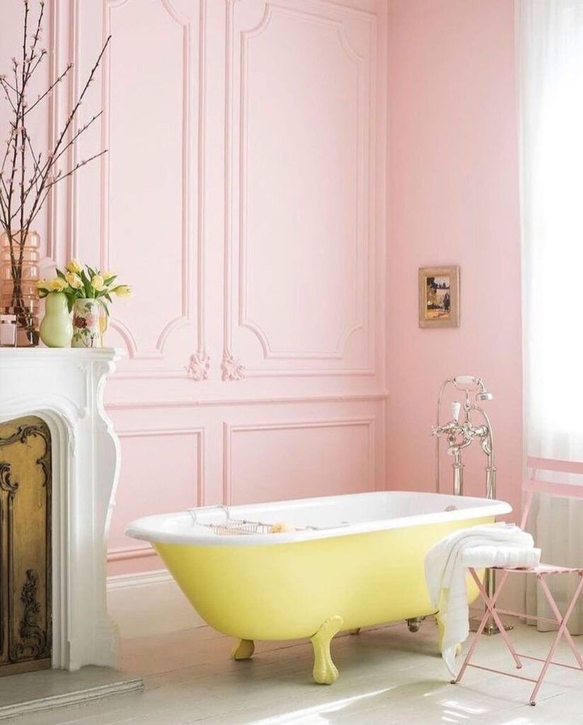 Pink bathroom with yellow clawfoot tub and vintage fireplace.