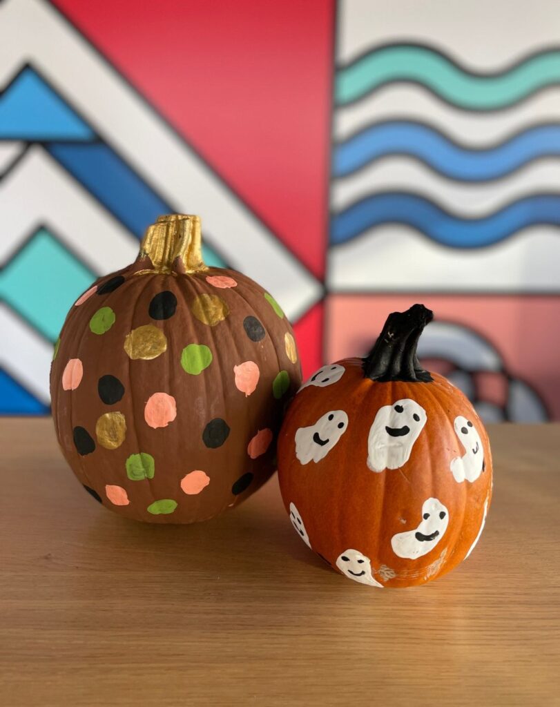 Two painted pumpkins one with polka dots another with ghost designs.