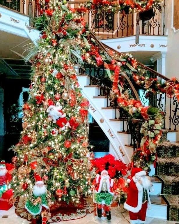 Traditional red and gold Christmas tree with Santas beside decorated spiral staircase