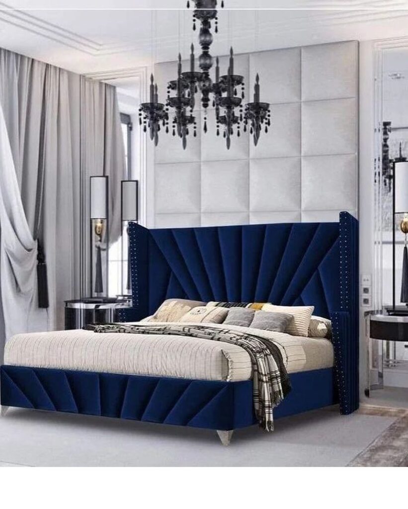 Navy tufted bed with black chandelier in white Victorian room