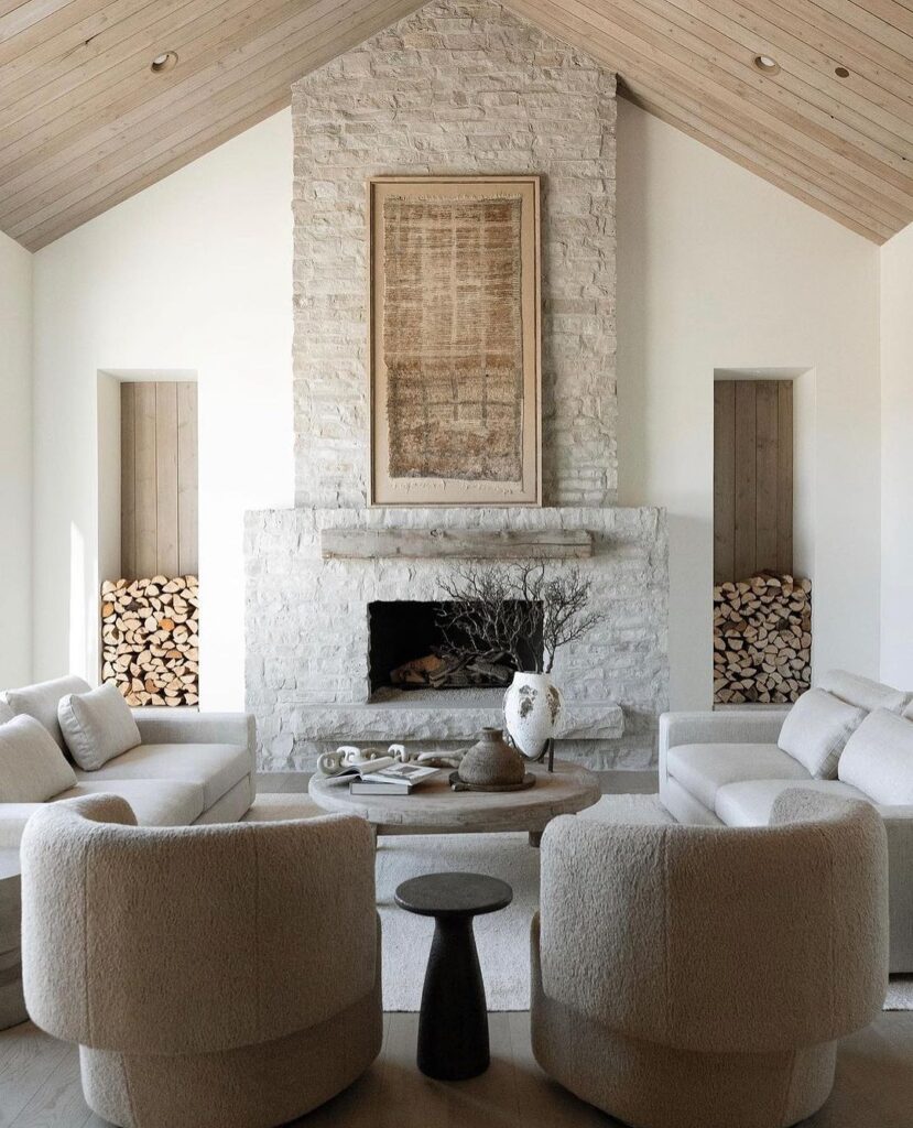 Living room with vaulted ceiling, stone fireplace, and cozy white furniture.