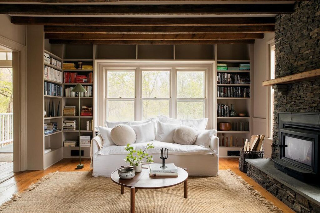 Bohemian living room with wooden beams bookshelves and white sofa
