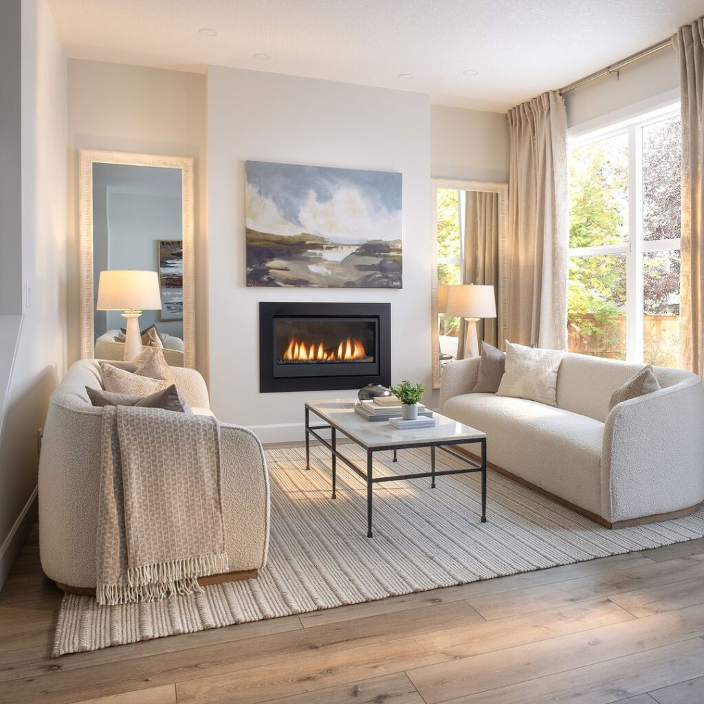 Cozy living room with fireplace, coastal artwork, and cream-colored furniture.